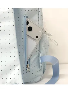 Detailed shot of a cute polka dot backpack showing the side zipper pocket with phone storage.
