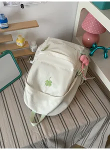 Minimalist white casual backpack detail with cute clover embroidery and pendant charm.