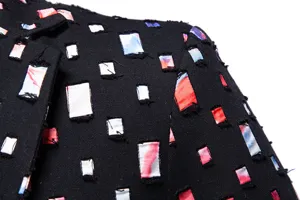 Dettaglio della giacca da uomo nera con inserti patchwork colorati e strappati.