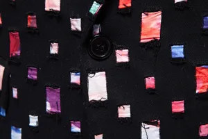 Primo piano di giacca da uomo per spettacolo con dettagli colorati e bottone nero centrale.