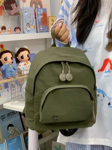 Detail view of mini green nylon backpack with front pocket and cute zipper pulls in daily use.