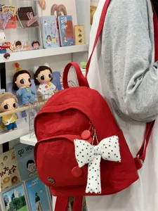 Red mini backpack detail featuring a cute white polka dot bow, perfect for casual daily summer outings.
