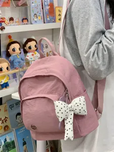 Pink mini backpack for women, cute casual daypack with polka dot bow charm and lightweight nylon.