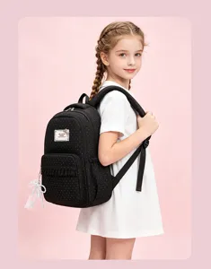 Detail view of a black polka dot school backpack with a cute lace pendant and front pocket.