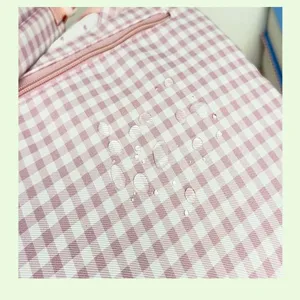 Pink gingham backpack detail close-up showcasing waterproof fabric texture and neat stitching.