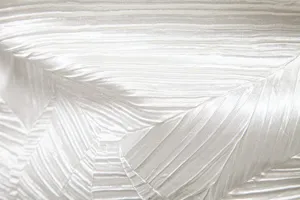 Detailed close-up shot of white pleated fabric showing delicate texture and fine craftsmanship.
