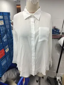 Detailed view of women white long sleeve shirt with chest pocket and lapel collar on mannequin.