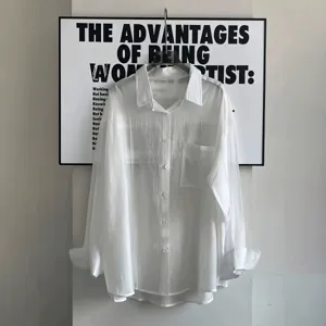Detailed view of a white sheer textured long sleeve shirt with front pocket and button closure.