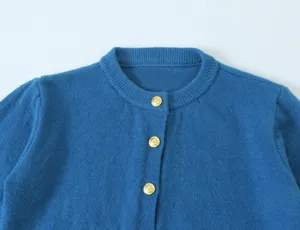Close-up van een chique blauwe gebreide vest met elegante goudkleurige metalen knopen.