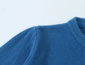 Detailopname van de schouder en kraag van een blauwe gebreide trui met fijne textuur.