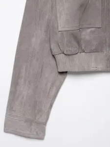 Graue Wildlederjacke Detailansicht mit Textur, Tasche und Rippbündchen für Damen.