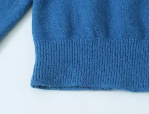 Gedetailleerde close-up van de geribbelde zoom en mouw van een blauw gebreid vest.