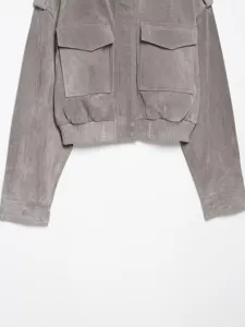 Nahaufnahme einer grauen kurzen Wildleder-Stil-Jacke mit Pattentaschen und Schulterklappen.