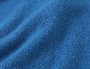 Close-up van blauwe zachte gebreide stof, ideaal voor gezellige dames vest kledingdetails.