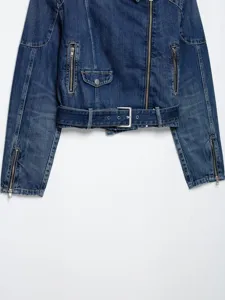 Detailweergave van het denim bikerjasje met asymmetrische rits en metalen riemgesp.
