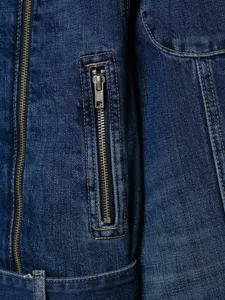 Detail van een spijkerjas met metalen rits en contrasterende stiksels in donkerblauw.