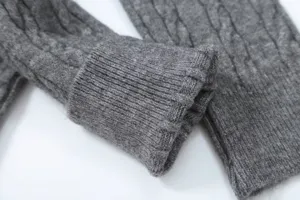 Grey cable knit sweater detail close-up, soft textured long sleeve winter fashion knitwear.