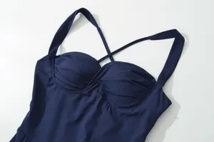 Primo piano dettagliato di un elegante abito blu scuro con bustino arricciato e sottili spalline.