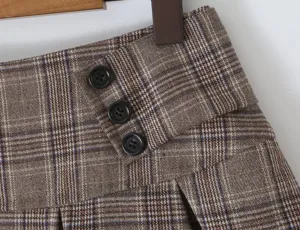 Brown plaid pleated skirt detail view, showing classic pattern, wide waistband and buttons.