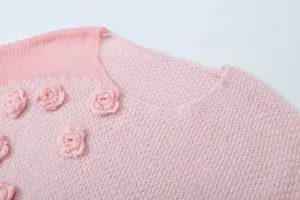 Rosa Strickwaren Detail mit 3D Blumen Applikationen, weiche Textur und Kragen Design.