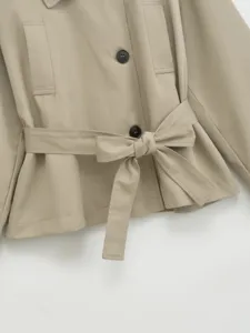 Khaki trench coat waist belt detail, closeup view showing stylish lapel and button features.