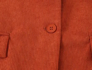 Orange corduroy blazer fabric detail view showing button and pocket close up texture