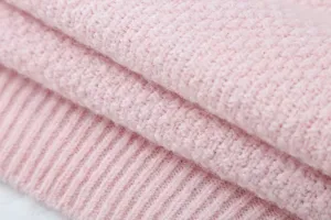 Nahaufnahme der rosa Strickstoff-Textur mit weicher Wolle und gerippten Bündchen.