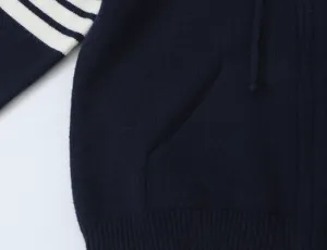 Primo piano sui dettagli del cardigan in maglia blu scuro con maniche a righe bianche.