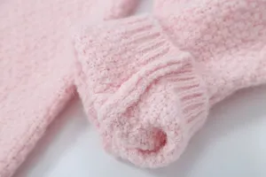 Nahaufnahme eines weichen rosa Strickpullover Bündchens mit feiner Textur und Rippenmuster.
