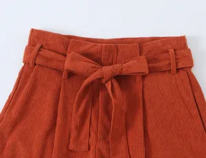 Detail view of high waist corduroy trousers waistband with elegant bow belt design.