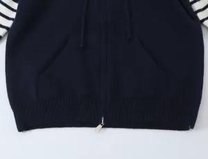 Dettaglio di felpa con zip in maglia blu scuro da donna con maniche a righe e tasche.