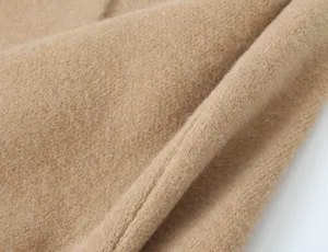 Close up detail of soft camel knit fabric texture, showing fine material quality and weave.