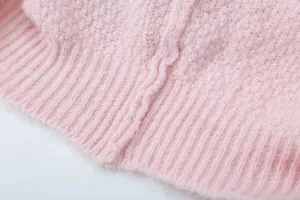 Detailaufnahme der weichen rosa Strickpullover Textur mit geripptem Saum und Bündchen.