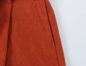 Close-up of stylish orange corduroy pants, premium texture detail shot for women.