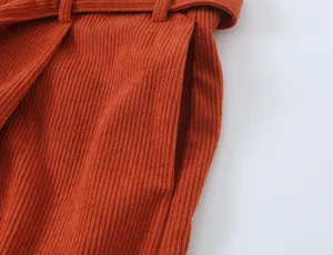 Detailed close-up of women orange corduroy trousers featuring pocket and waistband design.