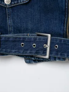 Close-up detail van de denim bikerjas zoom voor dames met metalen gesp en oogjes.