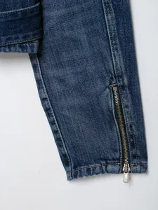 Details van de mouw van een spijkerjas voor dames met blauwe wassing en metalen rits.