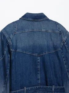 Detailweergave van de achterkant van een blauwe denim bikerjas met stiksels en riemlussen.