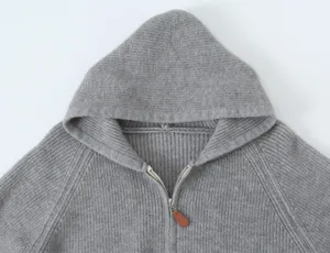 Vue détaillée d'un gilet en tricot gris à capuche avec fermeture éclair métallique.