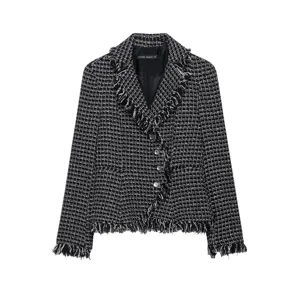 Black and white tweed blazer detail featuring fringe lapel and button closure close-up.