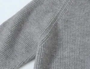 Vue de détail d'un pull en tricot côtelé gris montrant la texture et la couture d'épaule.