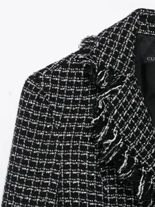 Close-up black and white tweed blazer jacket detail, textured fabric with frayed lapel.
