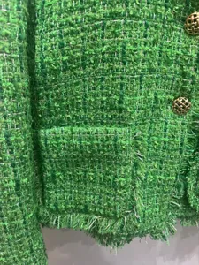 Green tweed fringe jacket detail shot, elegant women's short coat with gold buttons.
