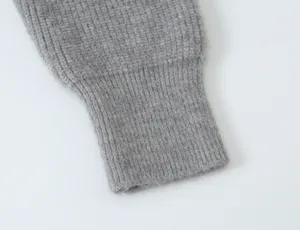 Détail de poignet de pull en tricot gris avec texture côtelée, gros plan épuré et minimaliste.