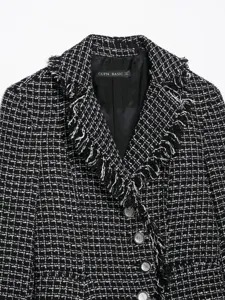 Black and white tweed blazer detail featuring frayed lapel and retro button closure.