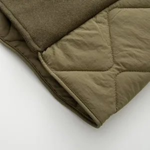 Detail shot of women's quilted parka coat, green spliced fabric, stylish winter outerwear.