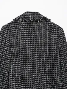 Close-up detail of black and white tweed blazer collar with chic fringe trim and textured fabric.