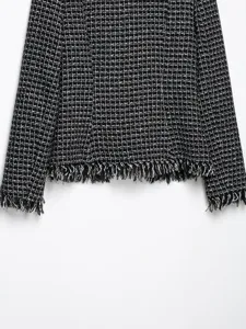 Black and white tweed jacket detail showing textured fabric and stylish fringed hemline.