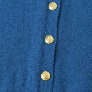 Blauwe gebreide damesvest met elegante gouden metalen knopen, gestructureerd detailzicht.