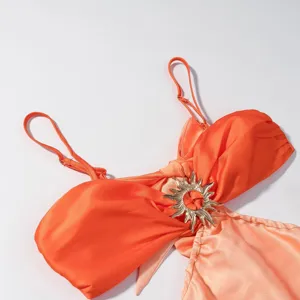 Detailansicht des orangefarbenen Kleides mit schicker Metall-Sonnenschnalle und dünnen Trägern.